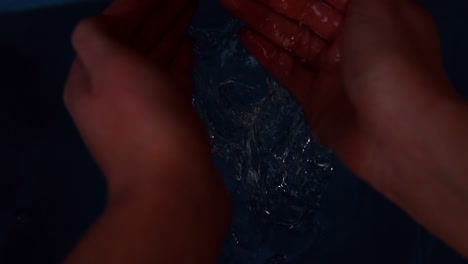 hands plunging into black water