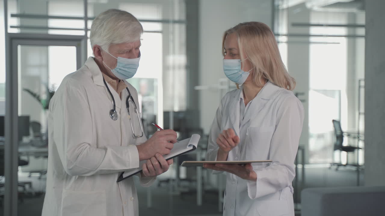 пара врачей в масках беседуют, просматривая результаты на планшете 1