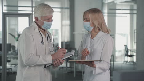 a pair of doctors with masks converse while looking at results on a tablet 1