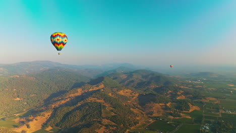 colorful hot air balloons soaring over the green hills. picturesque panorama of napa valley in california, usa. aerial view.