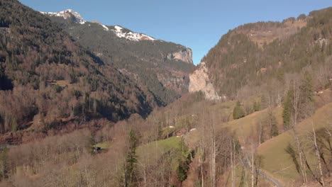 wide aerial shot of a scenic valley with snow covered mountains in the background