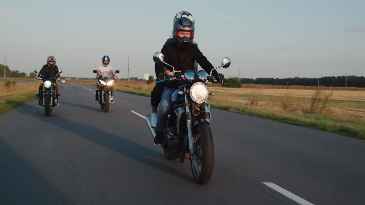 un grupo de ciclistas conduce por la carretera entre los campos en un claro día de otoño