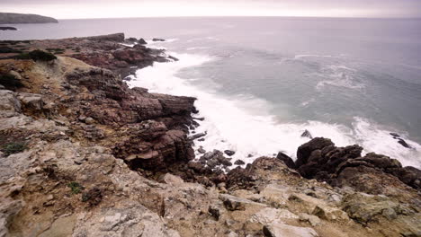 wide angle view of waves breaking into the rocky coastline