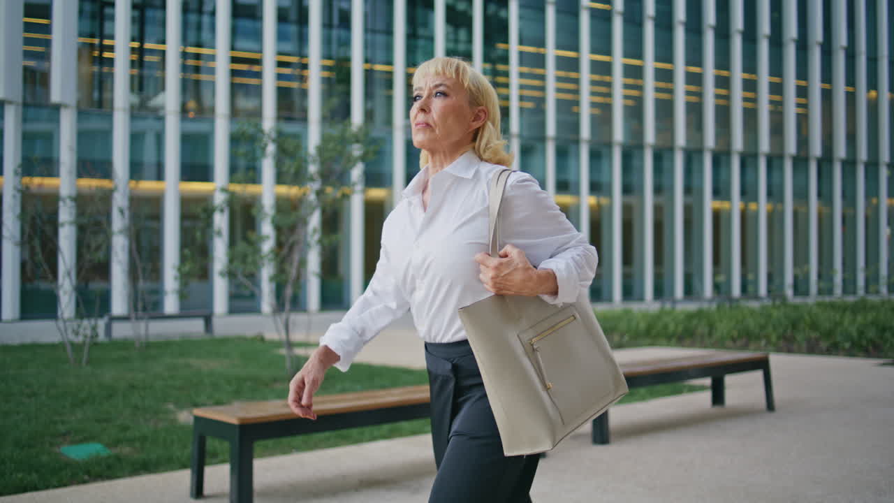 Confident pensioner walking street at office building. Aged businesswoman going