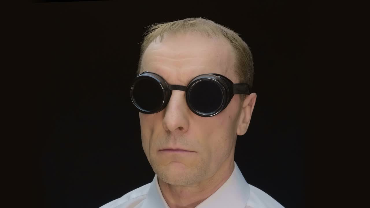 용접 할 때 밝은 불꽃으로부터 보호하기 위해 둥근 검은 안경을 입은 남자