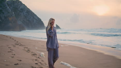ocean woman communicating smartphone walk shore. relaxed girl at cloudy sunset