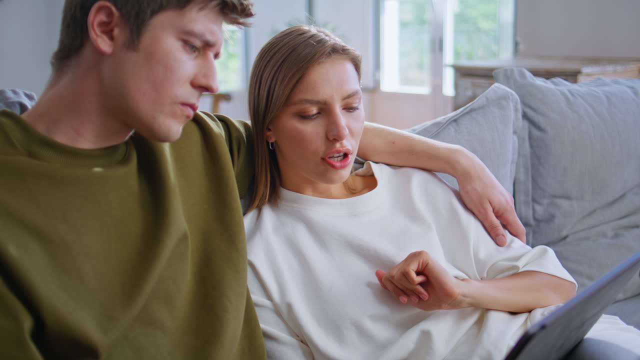 Young sweethearts surfing internet on tablet in room closeup. Couple embracing