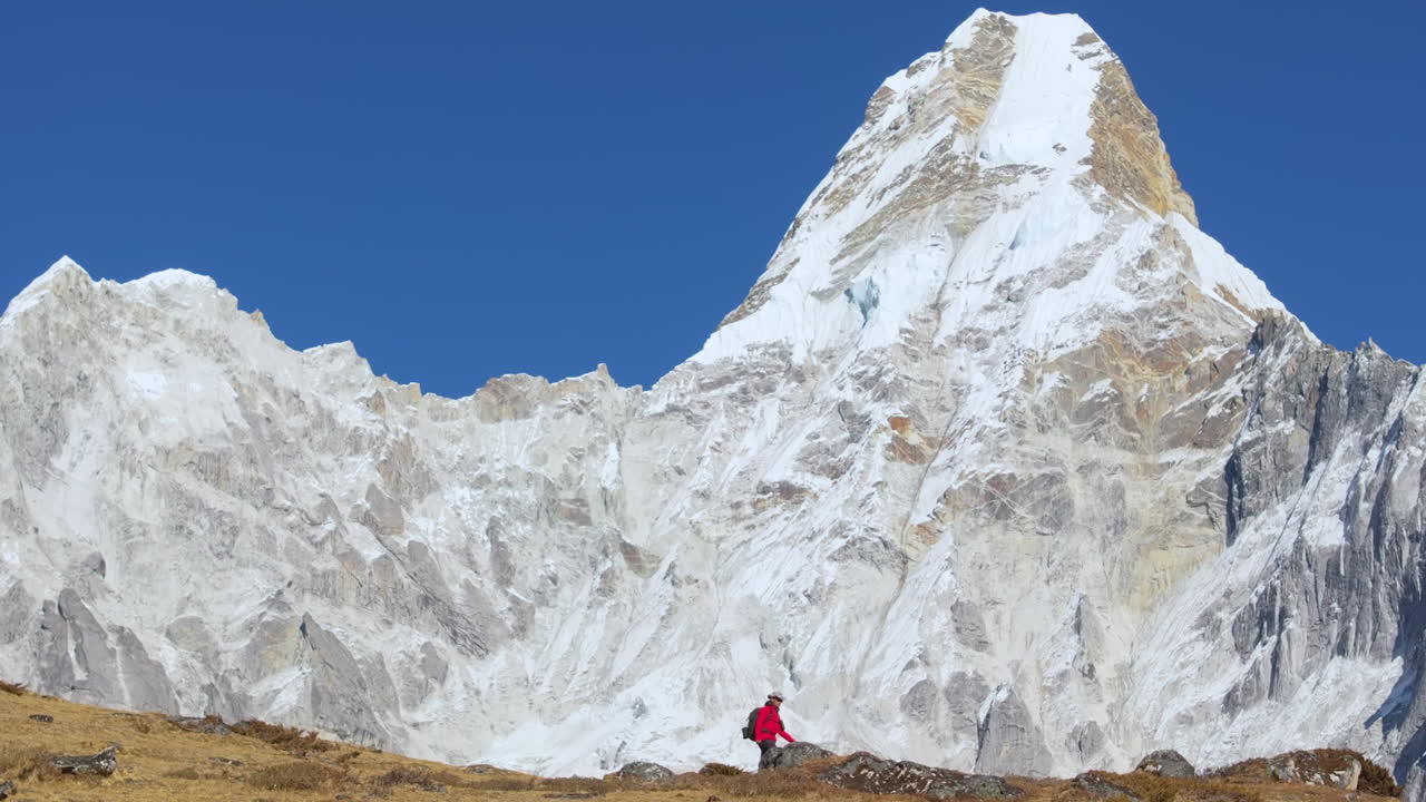 A solo trekker hikes along the ridge at the Ama Dablam viewpoint, pausing to admire the surrounding Himalayan landscape before continuing the journey toward Everest Base Camp, Nepal