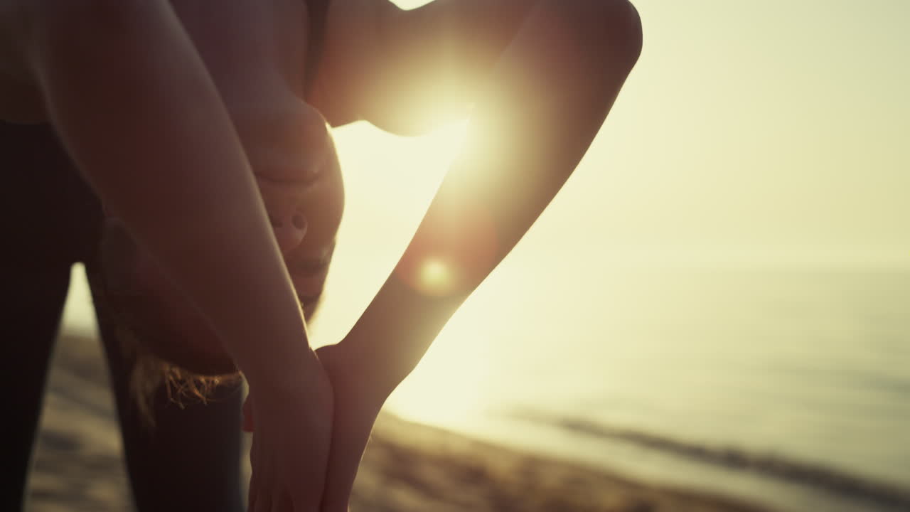 deportista haciendo una pose de puente practicando yoga en la playa en primer plano. chica estirándose