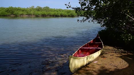 Canoa-Roja-Y-Blanca-Tirada-En-La-Arena-En-Los-Manglares-De-Puerto-Pizarro,-Tumbes-Peru