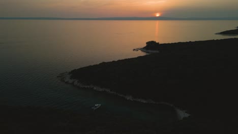 a boat anchored in a serene cove at sunset