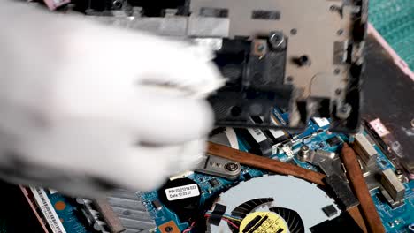 latino man wearing protective gloves cleaning his laptop with alcohol to remove dust and dirt