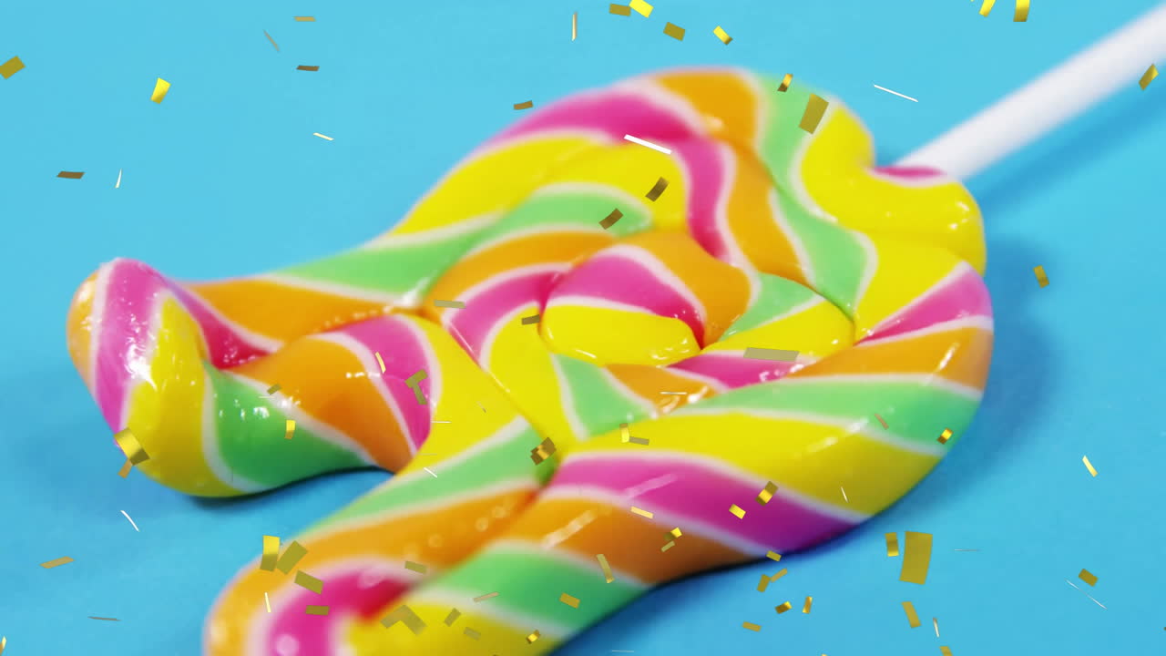 Confetti falling around colorful twisted lollipop on bright blue background animation