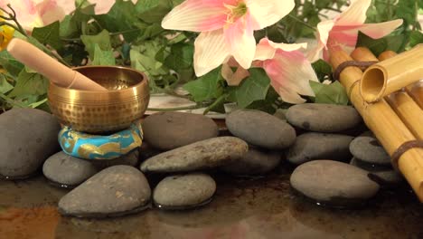 Tibetan-brass-bell-on-rocks-near-a-pound-with-a-fountain