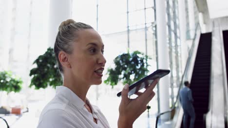 Businesswoman-talking-on-mobile-mobile-phone-while-standing-near-escalator-in-4k