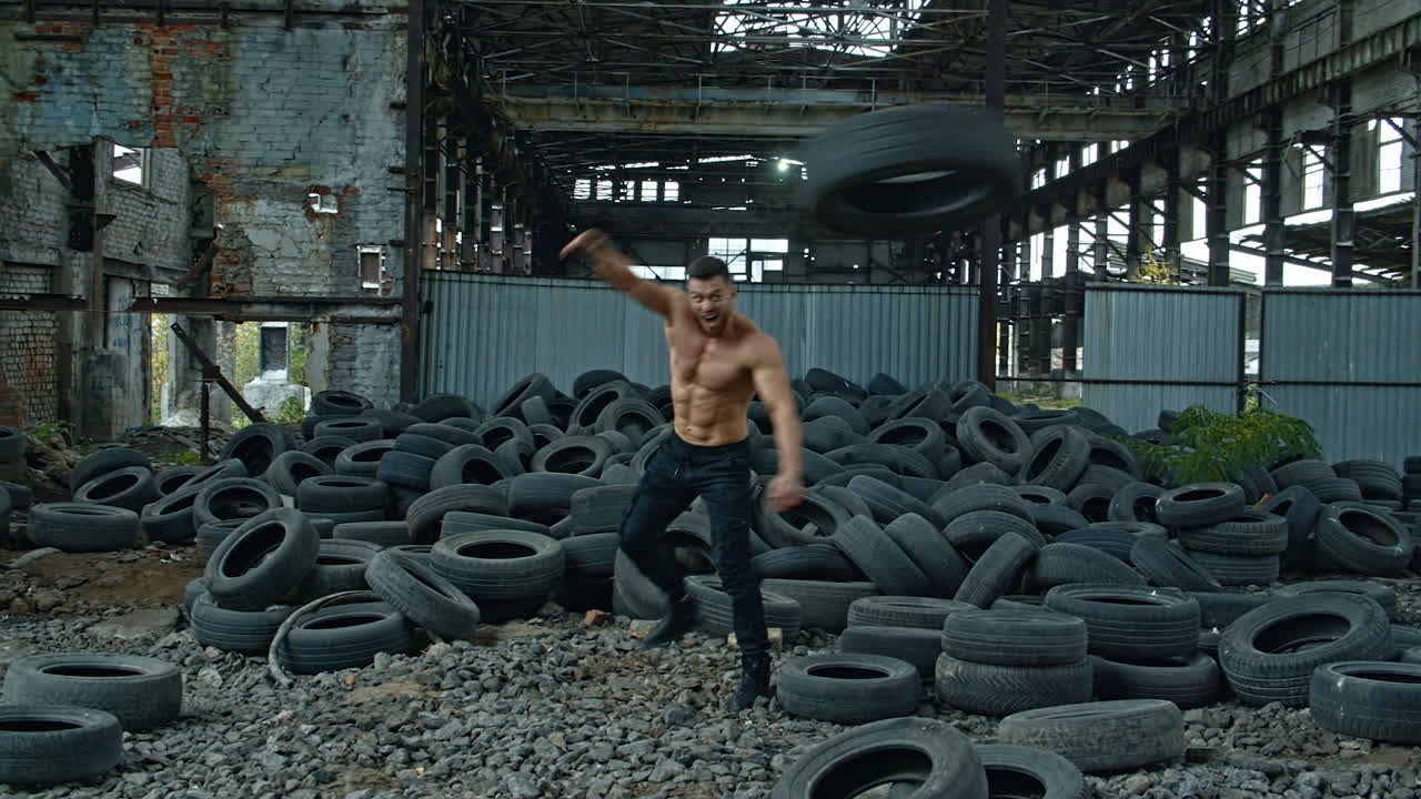 Muscular man throwing tire. Young muscular man working out with tire