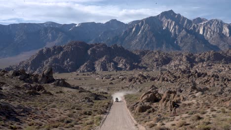 white off-road suv driving to the camera on a dirt road, away from the eastern sierra mountains, in the desert