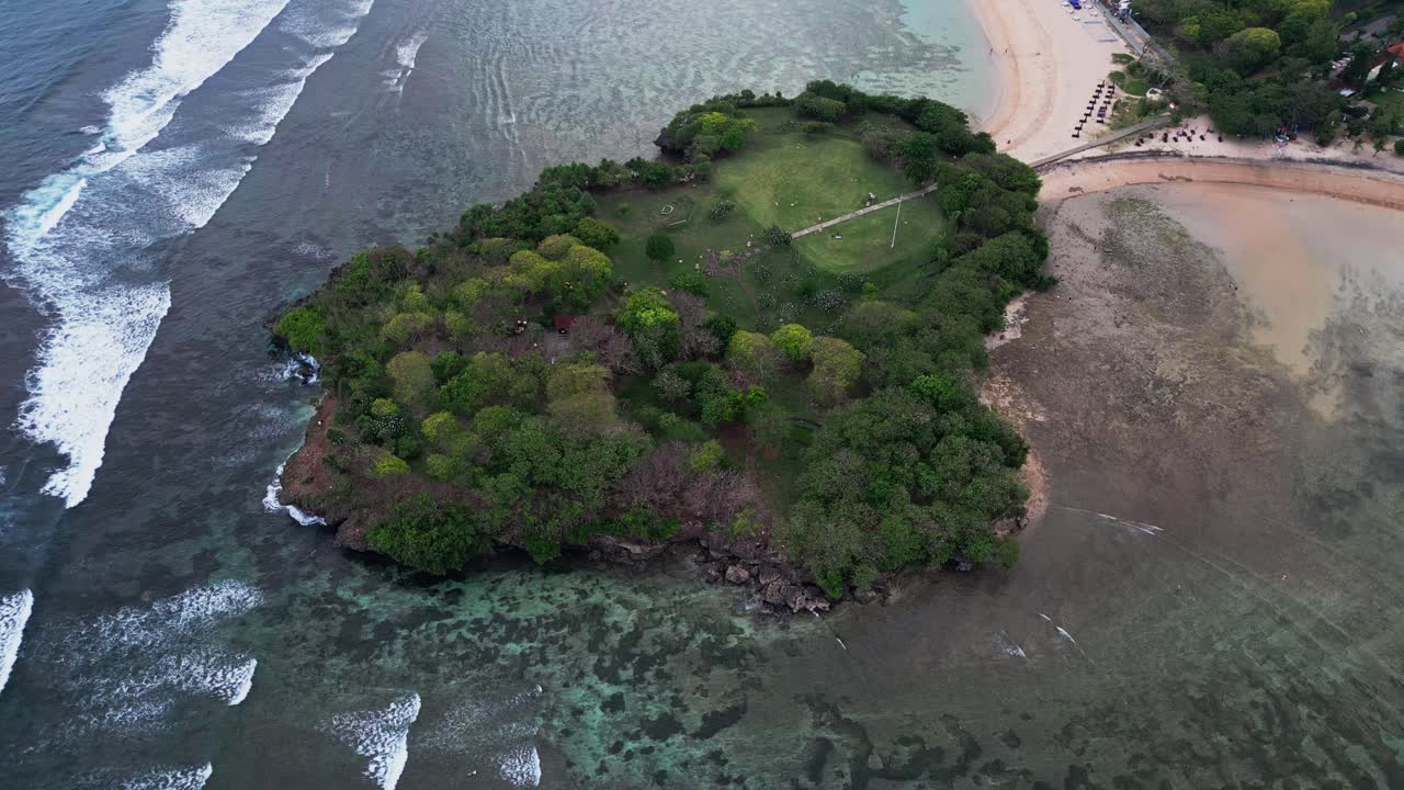 Overhead capture of a small tropical islet near the shore, encircled by coral reefs and calm waters, highlighting the natural beauty of coastal landscapes in a tranquil setting