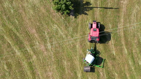 aerial view looking down over tractor wrapping bale in plastic on agricultural farmland