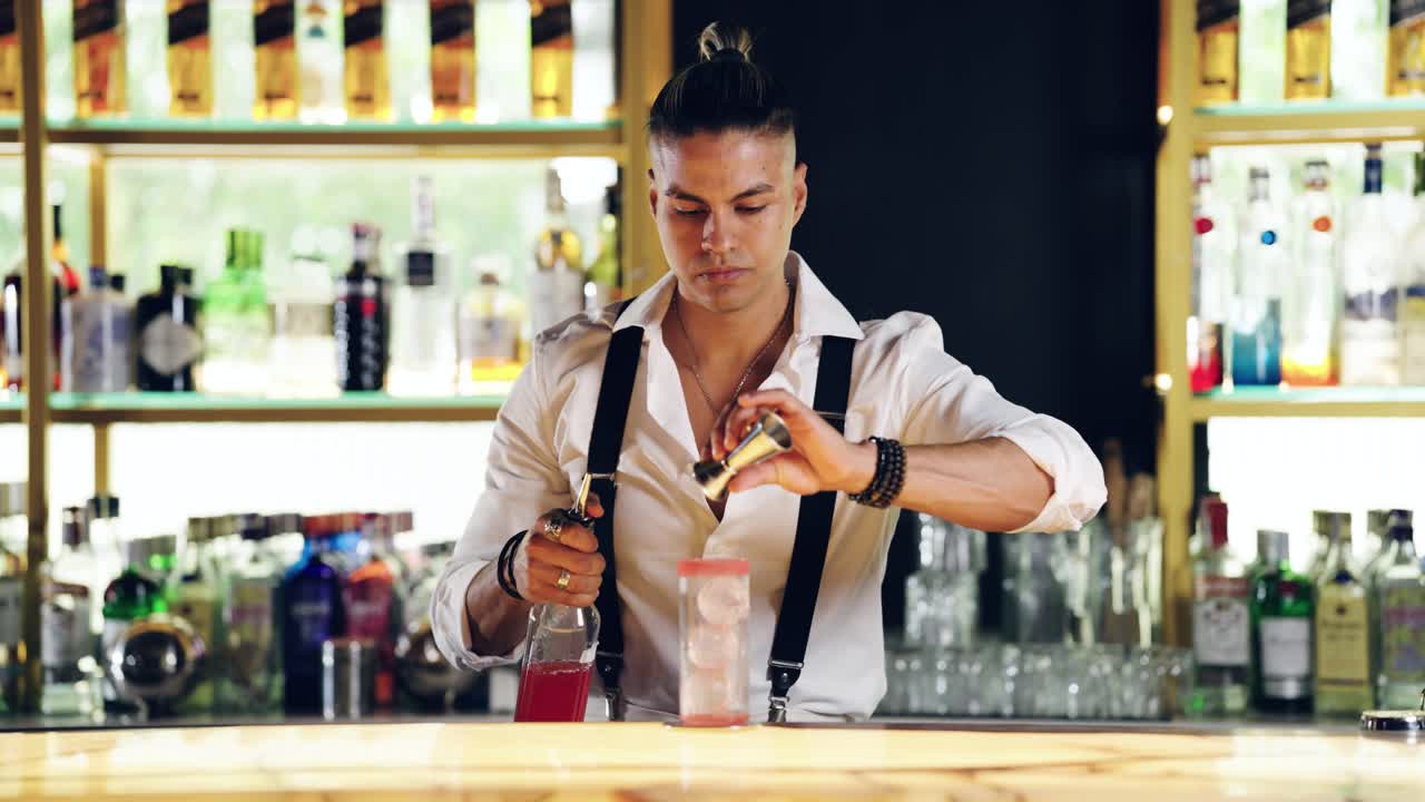 Professional Bartender Pouring Red Cocktail into Glass with Ice