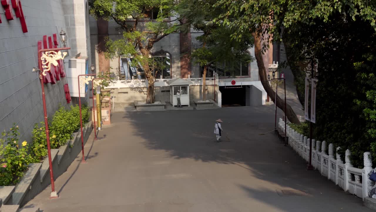Person brushing leaves from Fo guang shan street using broom made of tree branches, Cleaning urban area