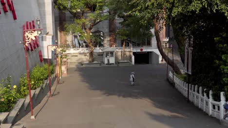 person brushing leaves from fo guang shan street using broom made of tree branches, cleaning urban area