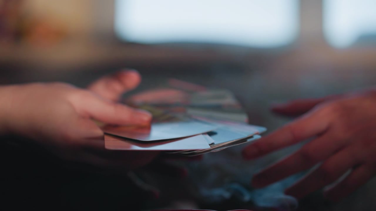 Hands exchanging tarot cards amid smoke, apprentice reader passes deck over velvet cloth, smoke curling from extinguished candle, closeup fingertips and nails, ritual rhythm, tense cinematic mood