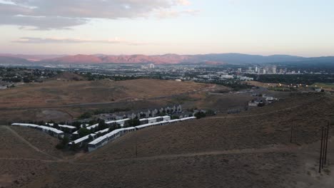 Aerial-shot-of-a-road-cutting-through-the-desert-leading-into-the-heart-of-Reno,-Nevada