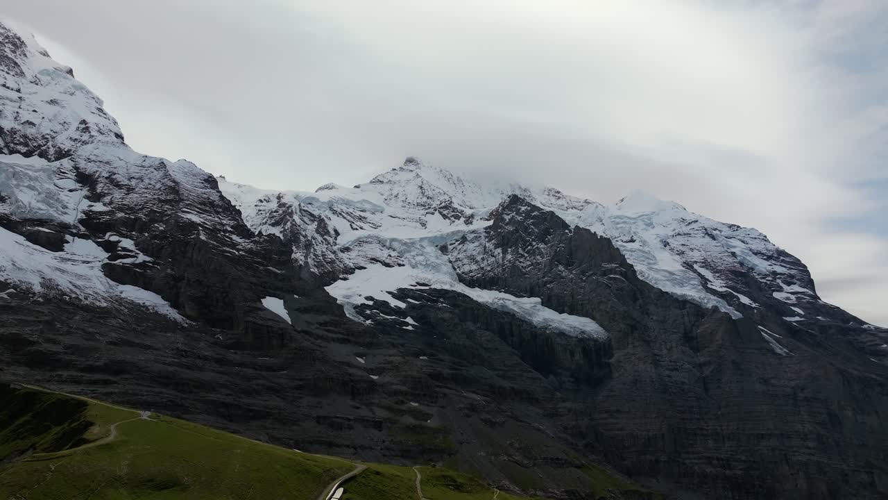 Aerial view of Eiger north face in the Bernese Alps, Switzerland, covered with glaciers, snow, and steep rock cliffs rising into the clouds