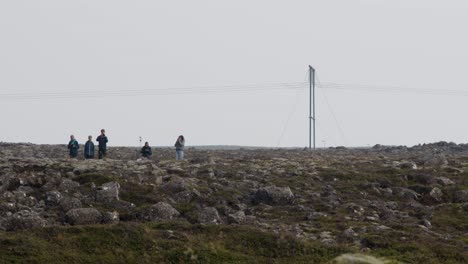 a group of people gathered in the rocky iceland landscape to witness the eruption of grindavik volcano in sundhnúkur crater.