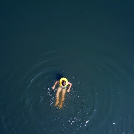aerial shot of a boy swimming in clear sea water. top view of a boy swimming away camera in the middle of the ocean