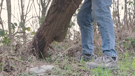 Man-with-Blue-Jeans-And-Mask-Moving-A-Log-Of-Wood-from-Brambles-During-Sunny-Day-In-Winter---Close-Up-View-in-Slow-Motion