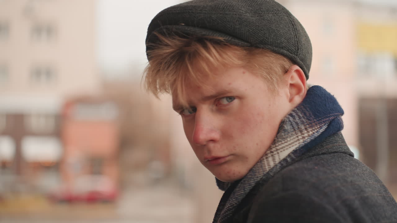 White creator on cold city street turns head with suspicious stare toward camera, wool scarf and cap, blurred downtown background, cinematic portrait framing, fashion editorial energy, detective mood