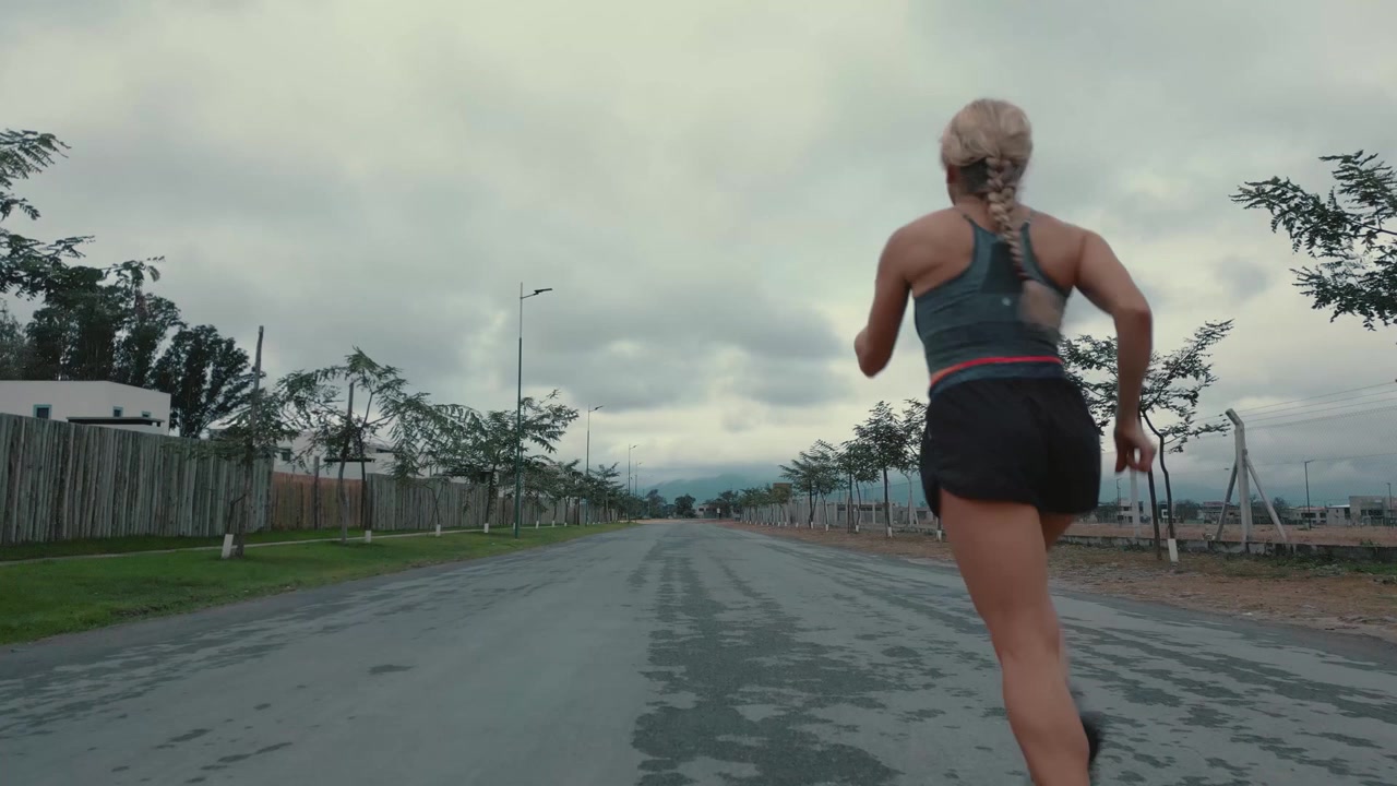 Giovane donna che fa jogging lungo una strada suburbana vuota