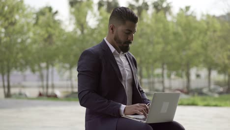 hombre de negocios enfocado trabajando con computadora portátil al aire libre