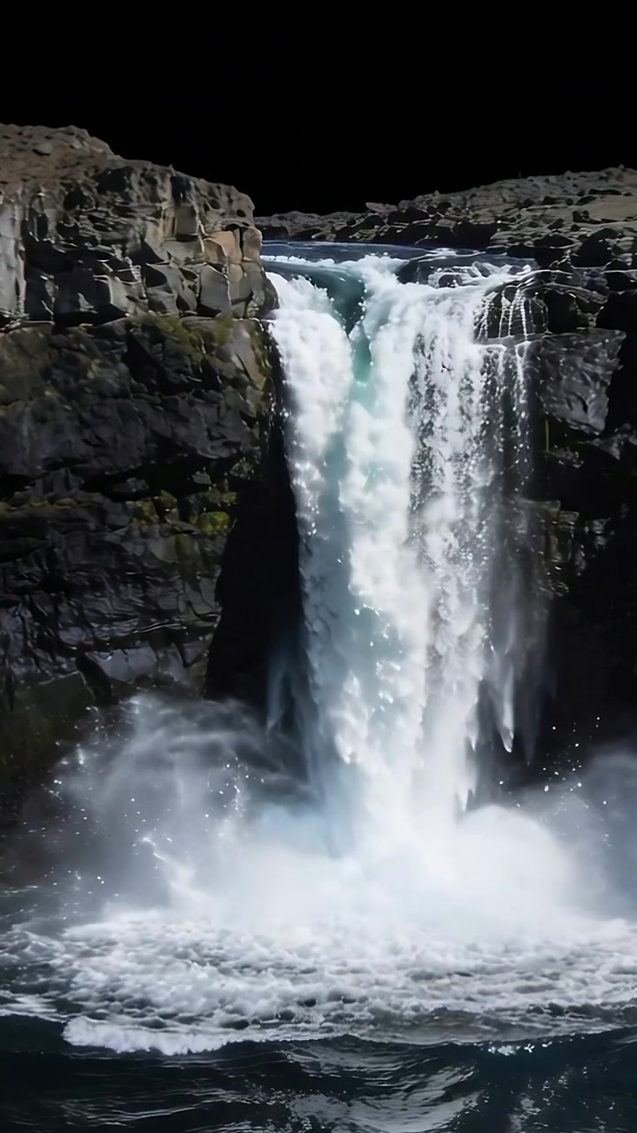Video verticale: Flusso impetuoso che spinge una cascata crescente e si getta in una pozza in una gola, creando schiuma.