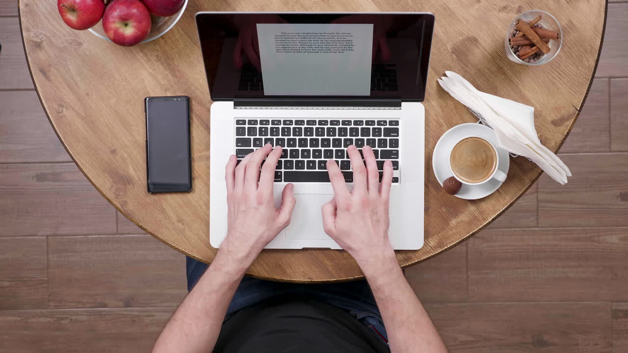 Person Typing on Laptop at a Cafe