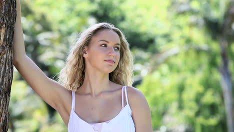 mujer sonriente apoyándose en un árbol