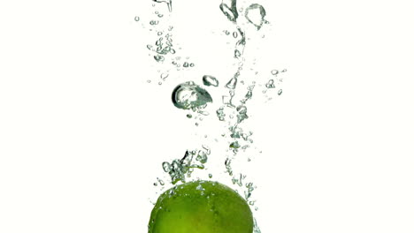 Manzana-Verde-Sumergiéndose-En-El-Agua-Sobre-Fondo-Blanco