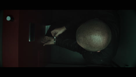 a bald dangerous looking man unpacks a black bag in the public toilet