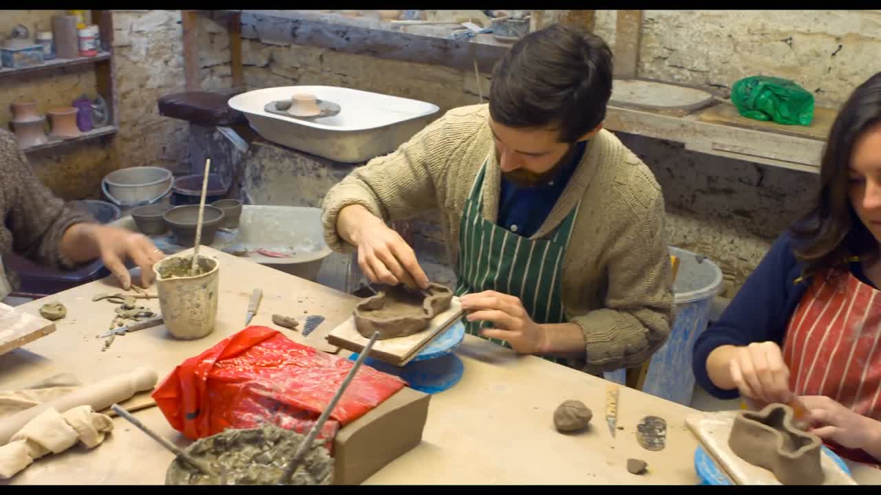 도자기 제작자 와 동료 들 이 진 ⁇  조각 을 하고 있다