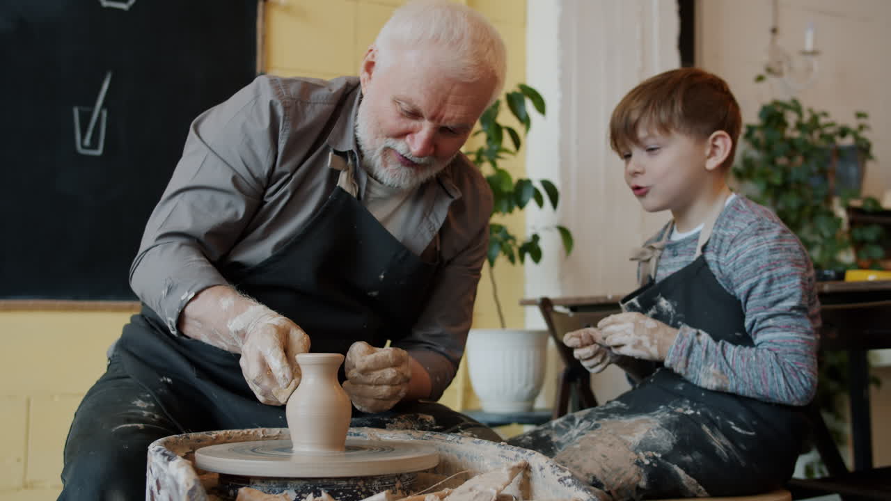 Nonno e nipote che modellano ceramica insieme