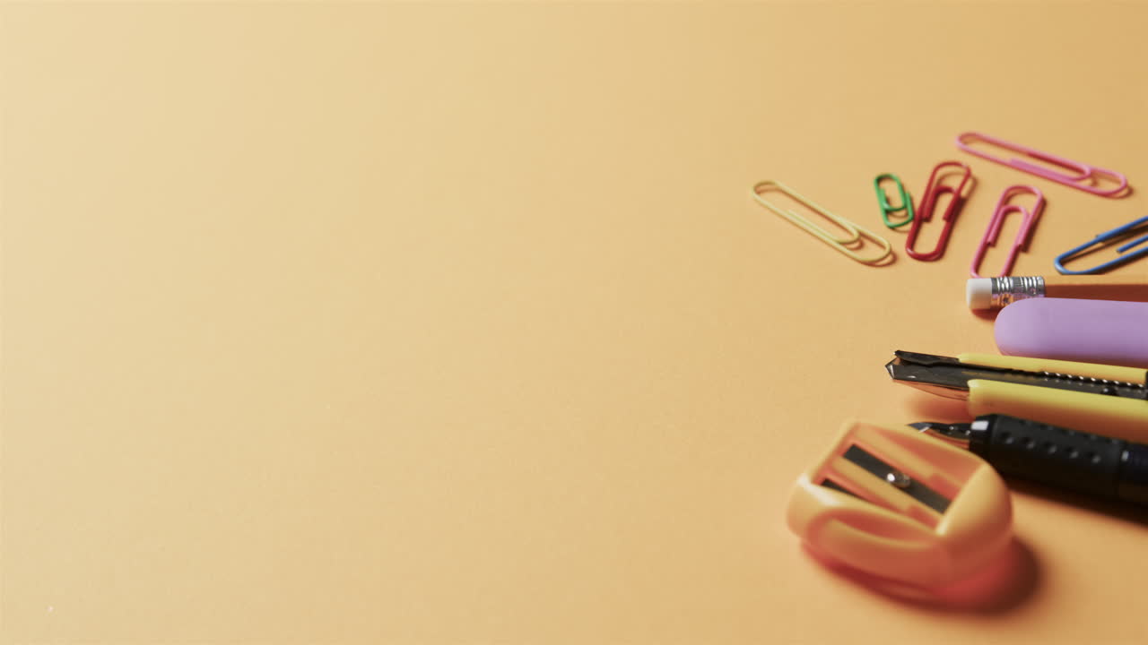 primer plano de papelería escolar colorida con espacio de copia en fondo beige, en cámara lenta