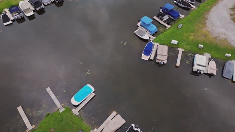 Boats-Moored-At-Jetty-In-Lake---aerial-top-down