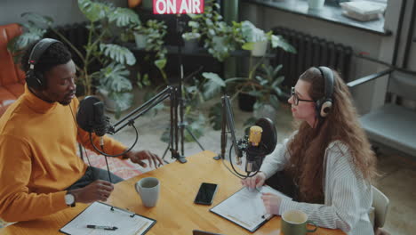 two cheerful co-hosts chatting and recording podcast episode in studio