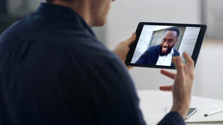 Primo piano di un manager che partecipa a una riunione da remoto tramite tablet con un partner. Videochiamata di un uomo