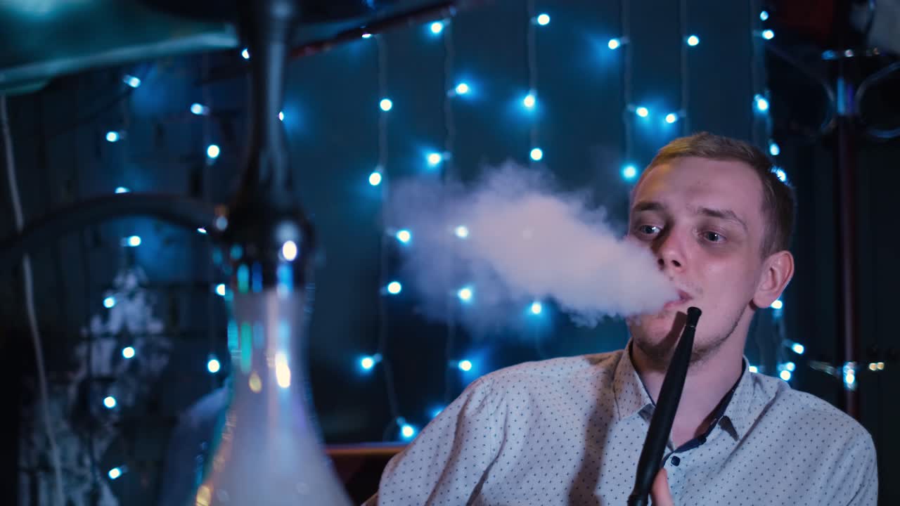 hombre fumando narguile en un club nocturno