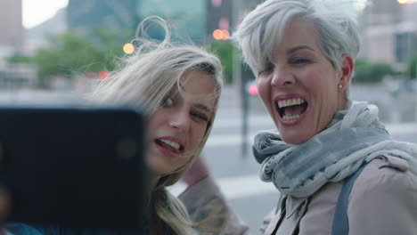 portrait of beautiful mother and daughter posing taking selfie photo using smartphone camera technology enjoying making faces together