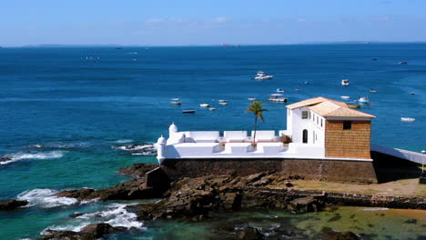 Aerial-view-of-Santa-Maria-Fort,-the-beach-with-many-blue-beach-umbrella-and-the-neighborhood-around,-Salvador,-Bahia,-Brazil