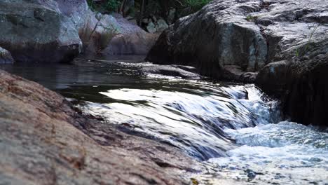 Paisaje-Prístino-De-Arroyo-Sedoso-Y-Brillante-Que-Fluye-Tranquilamente-Y-Bancos-Rocosos